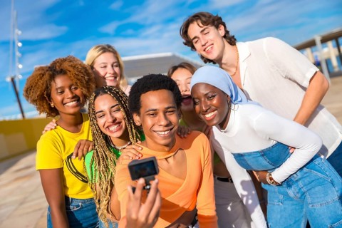 Frontal view of a transgender person talking a selfie with friends in an urban park