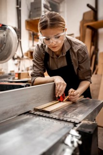 Female carpenter working studio with electric saw