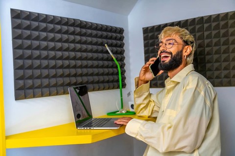Young modern man using laptop and talking to the mobile in a coworking space