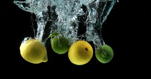 Yellow and Green Citrus, citrus limonum (Citrus aurantifolia), Fruits falling into Water against