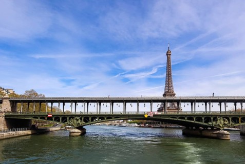 Eiffel Tower against blue sky with clouds and a bridge Pont de Bir-Hakeim (pont de Passy) over