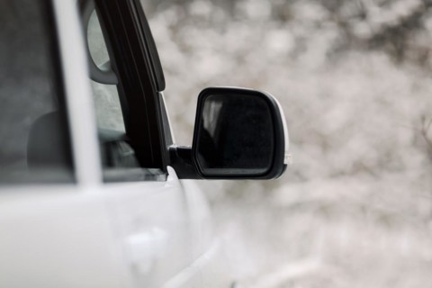 Soft focus of white vehicle with wing mirror parked in snowy countryside in winter