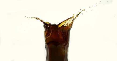 Ice Cubes Falling into Glass of Coke against White Background