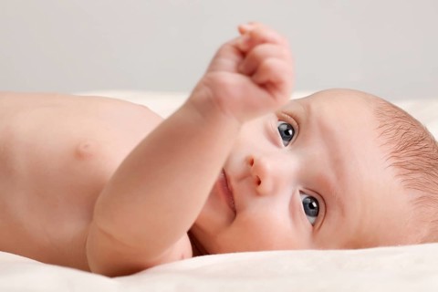 Ten weeks old cute little baby girl toddler with curious look on her face lying comfortably on bed