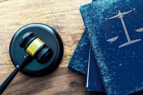 top view of judge gavel and stack of old law books with scales of justice on wooden table