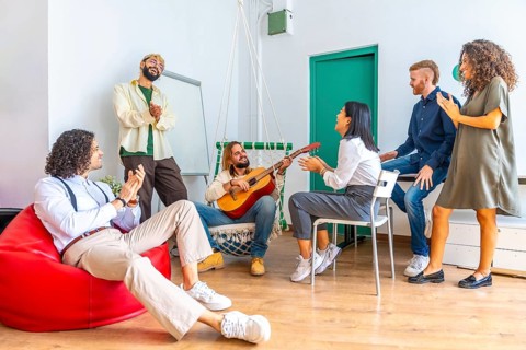 Distracted people singing and playing guitar during a break in a coworking