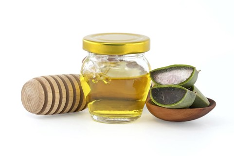 Aloe vera leaf slices showing the inside gel of the plant and honey isolated on white background,