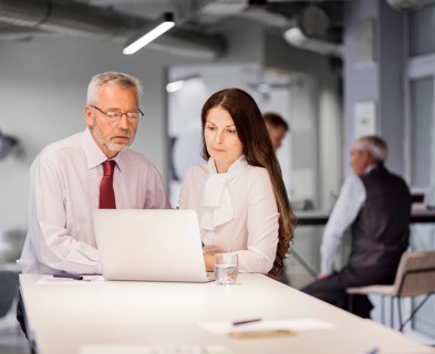 Senior businessman businesswoman looking laptop office