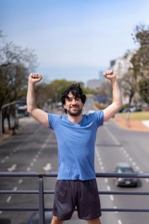 Successful man raising arms after running. Fitness male athlete with arms up celebrating success