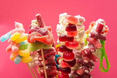 Variation of colorful fruit gums sweets skewered sour gummy bears on wooden skewers isolated on a