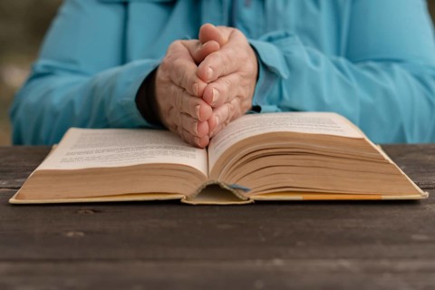 Woman with her hands on top of a holy book in prayer posture