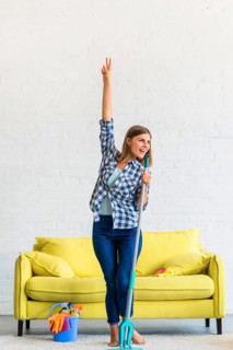 Happy woman dancing with mop home