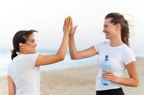 Side view two women high fiving each