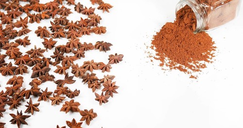 Star Anise (illicium verum), powder falling against White Background