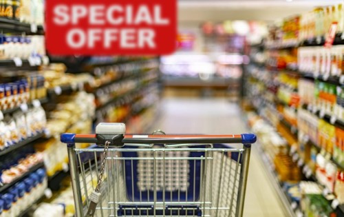A shopping cart by a store shelf in a supermarket