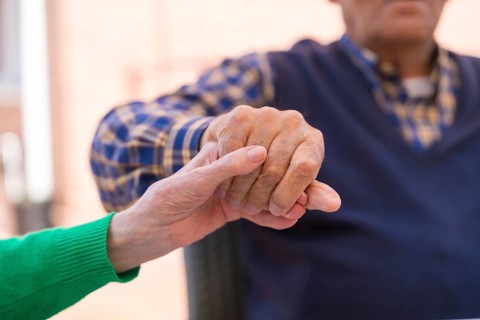 Detail of the hands of two elderly people in the garden of a nursing home or retirement home