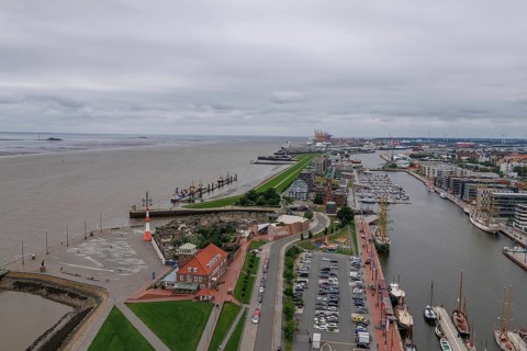 Panoramic view of a harbour town with a long dyke, streets and individual buildings along the