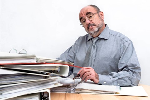 An arrogant civil servant sits behind his desk