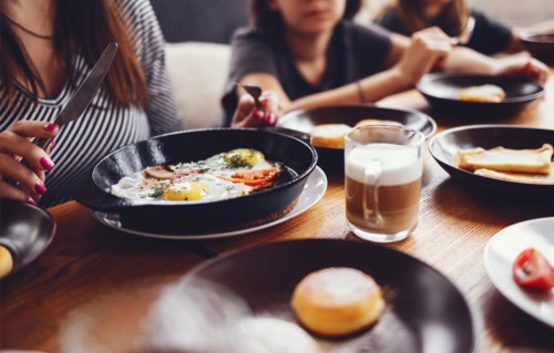 Hands taking pastries, vegetables, greens, cheeses, fried eggs, jams and tea in copper pot and