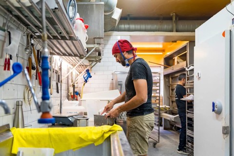 Male baker of bakery in the workshop of artisan bakery preparing the sourdoughs