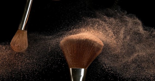 Make-up Brush spreading blush powder on black background