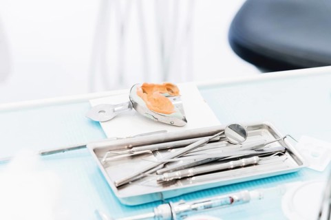 Close-up of a common stamotological instrument next to a metal form for prosthetics. Dental