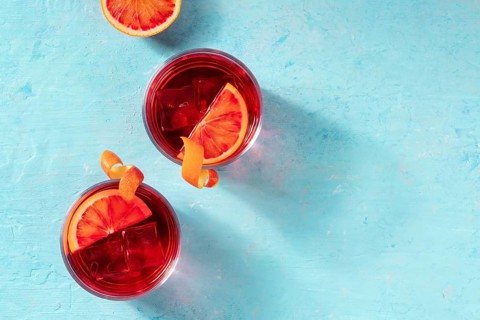 Negroni cocktails decorated with blood oranges, top shot on a blue background with a place for text