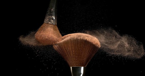 Make-up Brush spreading blush powder on black background