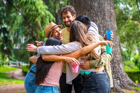 Multiethnic group of birthday party in the city park embraced in a symbol of friendship forever