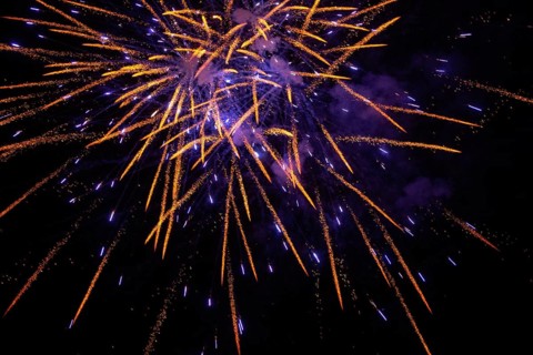 New Year's Eve fireworks night sky with golden and violet sparks
