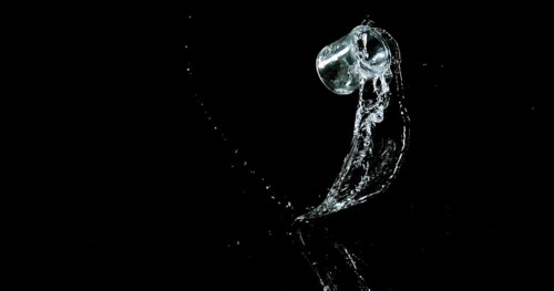 Glass of Water Bouncing and Splashing on Black Background