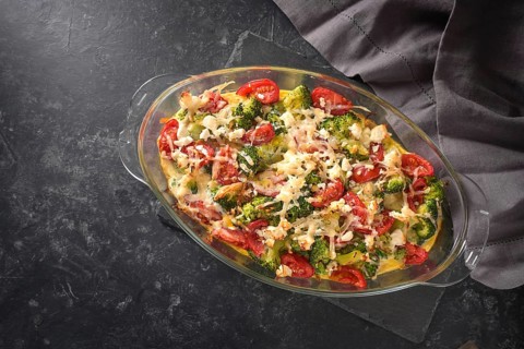 Casserole from broccoli, tomatoes, onions, feta and cheese, healthy vegetable dish on a dark gray