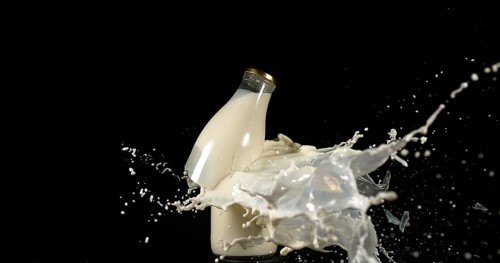 Bottle of Milk Exploding against Black Background