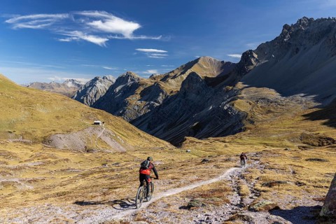 Alp Ramoz with Ramozhütte SAC, mountain biker on a trail, view into Welschtobel, behind Davos Alps