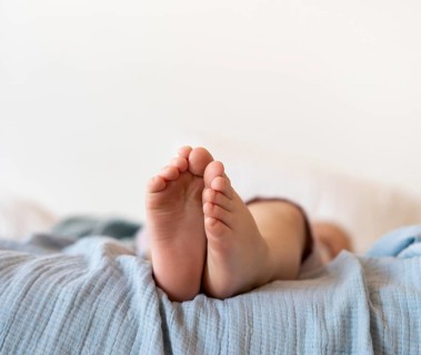 Close up baby feet sitting bed