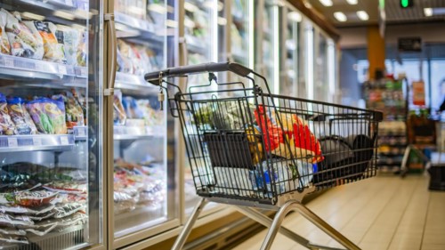 A shopping cart with grocery products in a supermarket