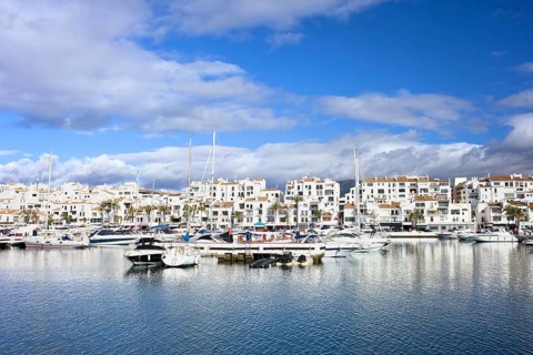 Marina waterfront with luxury motor yachts in holiday resort town of Puerto Banus on Costa del Sol,