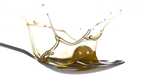 Olive Falling into Olive Oil against White Background