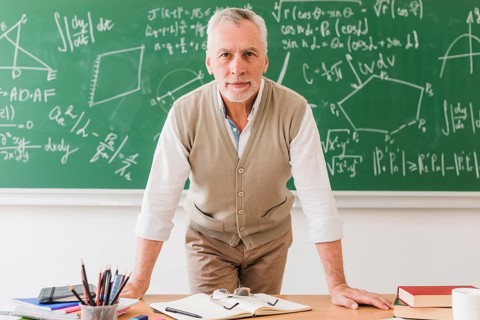Positive aged math teacher leaning desk