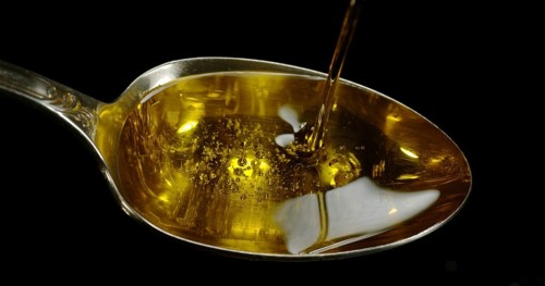 Olive Oil, Falling in a Spoon against Black Background