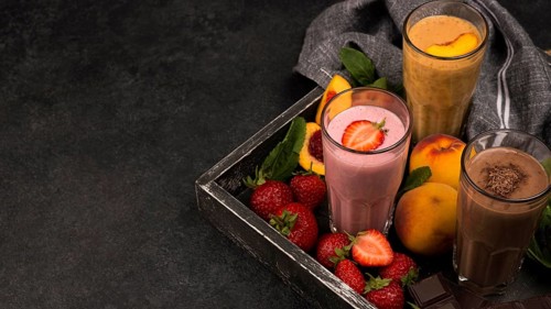 High angle milkshake glasses tray with chocolate fruits