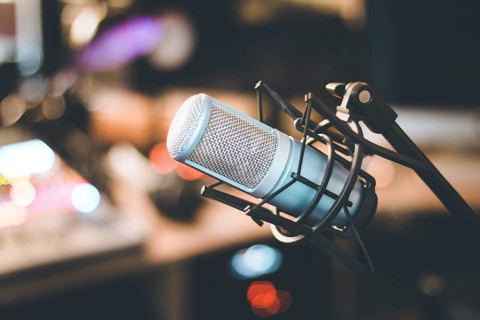 Microphone in a professional recording or radio studio, equipment in the blurry background