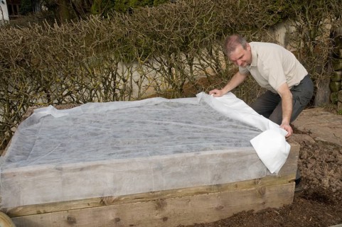 Man covers raised bed with fleece, mound bed, sowing, sowing, seeding