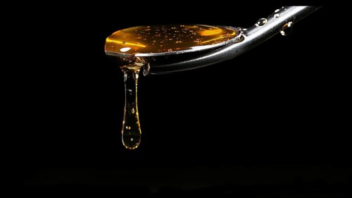 Honey Flowing from Spoon against Black Background