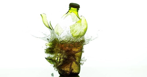 Bottle of Beer Breaking and Splashing against White Background