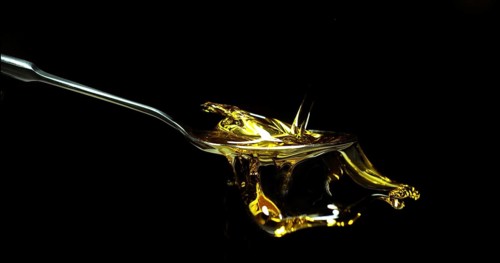 Olive Oil, Falling in a Spoon against Black Background