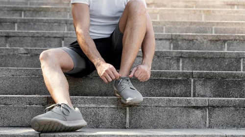 Front view man tying her shoelaces before exercising