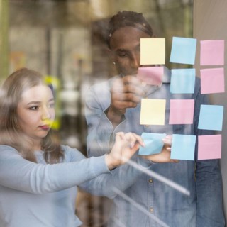Front view man woman putting sticky notes office window