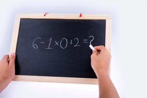 Hand writing a math problem on board with a chalk