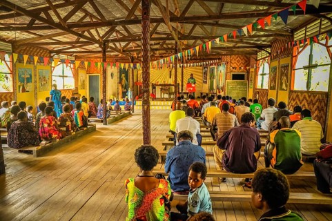 Palembe, Papua New Guinea, July 2015: Photo of native people sitting on wooden benches during mass